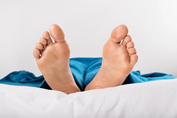 Odpočívající samičí nohy pod modrou přikrývkou — Stock fotografie