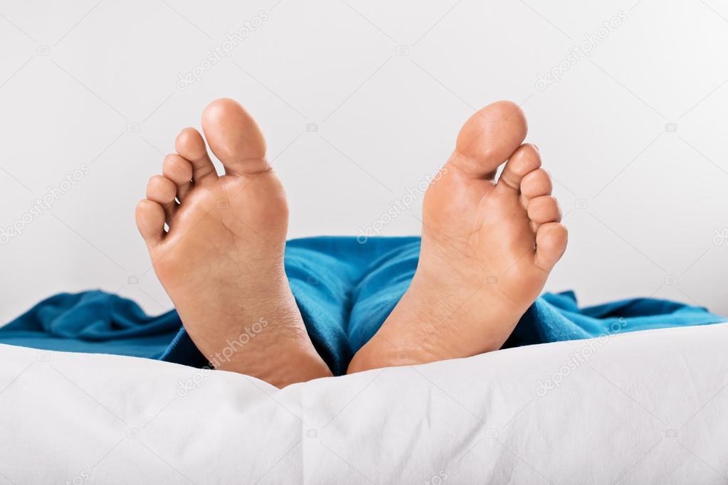 Resting female feet under blue blanket