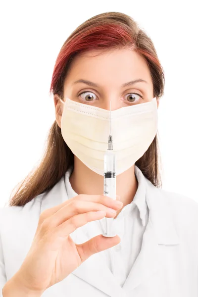 Jovem médico usando máscara cirúrgica e segurando uma seringa — Fotografia de Stock