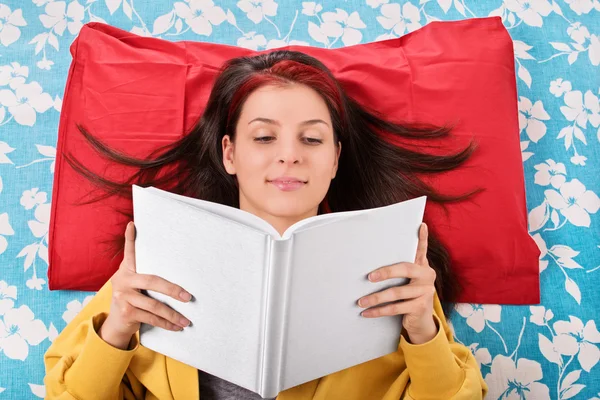 Jovencita leyendo un libro en su cama — Foto de Stock