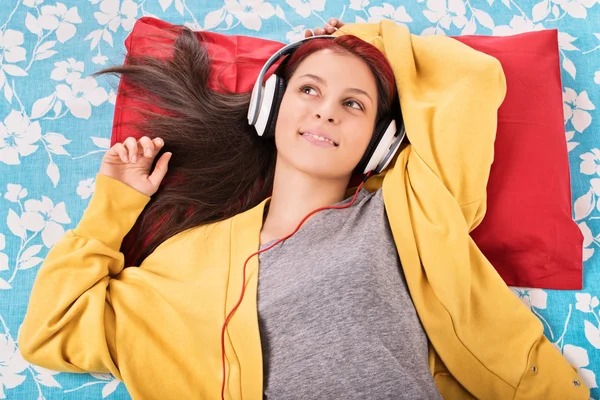 Jong meisje luisteren naar muziek op haar bed — Stockfoto
