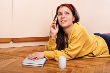 Young woman lying on the floor and talking on the phone