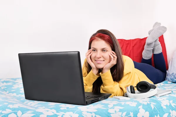Молодая девушка в своей комнате смотрит что-то на ноутбуке — стоковое фото