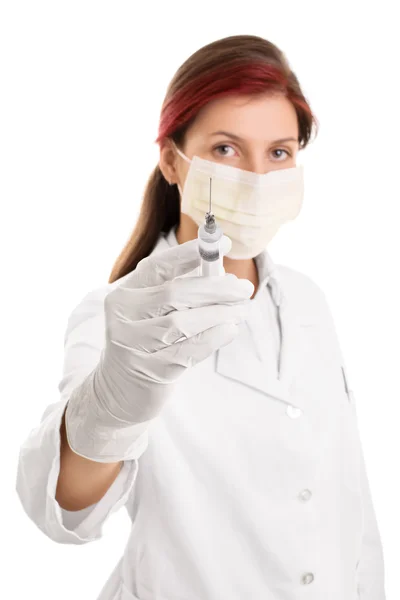 Young doctor wearing surgical mask and holding a syringe with a needle Royalty Free Stock Photos