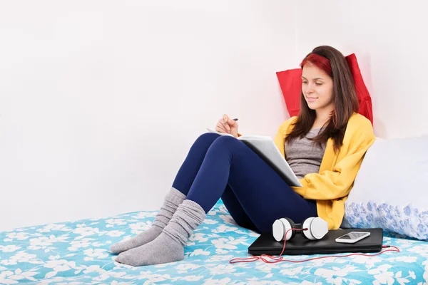 Girl in her bed writing something — Stock Photo, Image