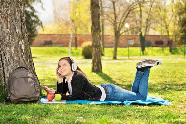 Молодая девушка слушает музыку в парке — стоковое фото