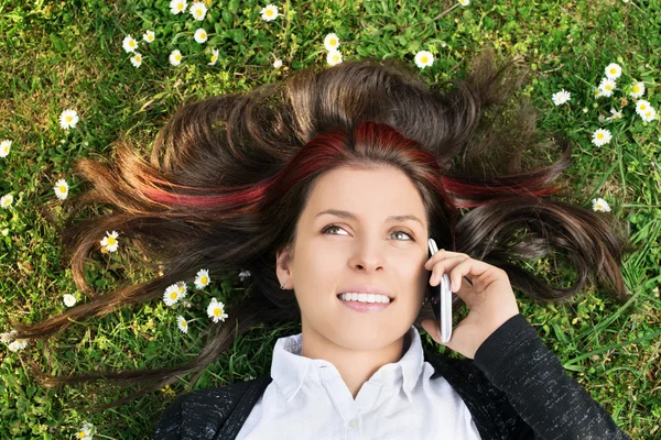 電話で話して、草原に横たわっている少女 — ストック写真