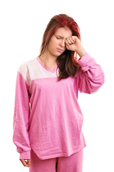 Sleepy girl in pink pajamas rubbing eyes
