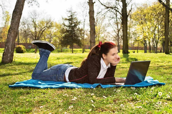 Mladá žena pracuje na svém notebooku v parku — Stock fotografie