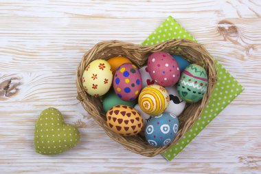 ahşap zemin üzerinde sepetteki renkli Paskalya yumurtaları