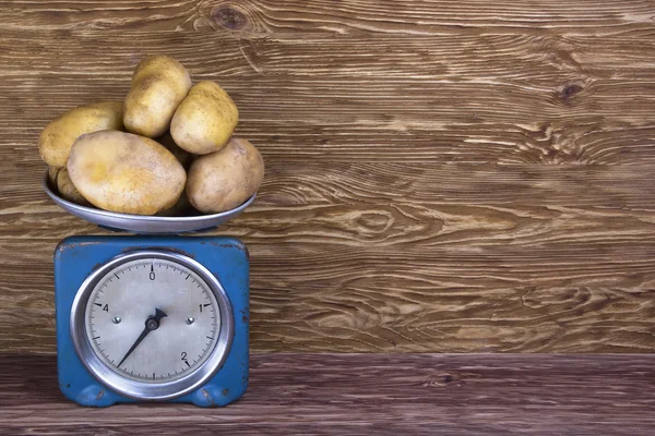 Batatas frescas em escala vintage e fundo de madeira — Fotografia de Stock