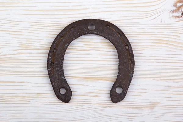 Old rusty horseshoe on a wooden background.