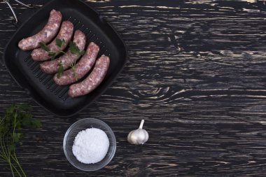 tavada ahşap zemin üzerine sarımsaklı çiğ sosis