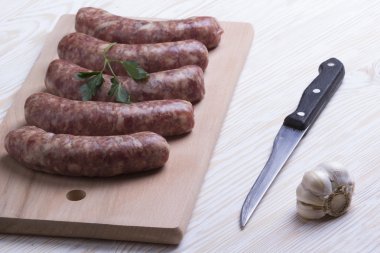Çiğ sosis, bıçak ve sarımsak ahşap tablo