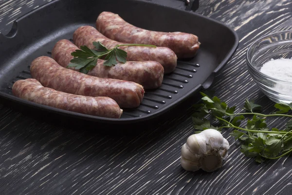 çiğ sosis tava, tuz ve sarımsak, ahşap arka plan