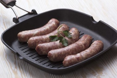 bir tavada, ahşap arka plan üzerinde çiğ sosis