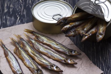 Ahşap arka plan üzerinde füme capelin ve konserve teneke