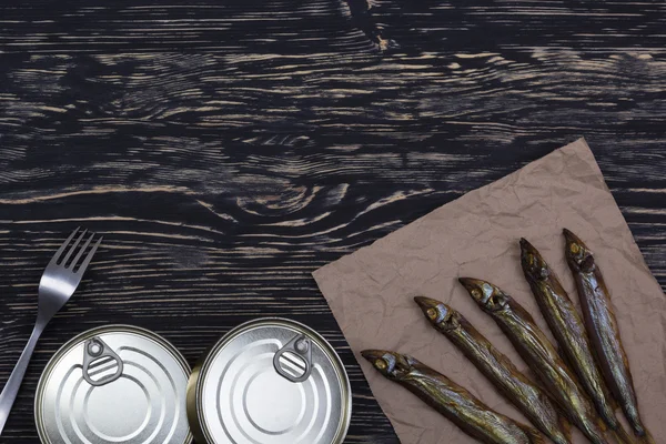 Ahşap arka plan üzerinde füme capelin ve konserve teneke