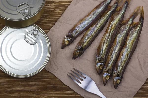 Smoked capelin and conserve tins on wooden background — Stock Photo, Image