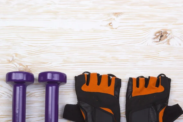 Haltère et gants de fitness sur fond bois — Photo