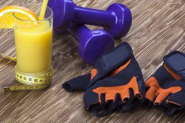 Haltères, jus d'orange, gants de fitness et ruban à mesurer — Photo