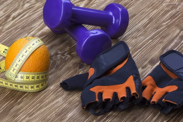 Primer plano de pesas, naranja, guantes de fitness y cinta métrica — Foto de Stock