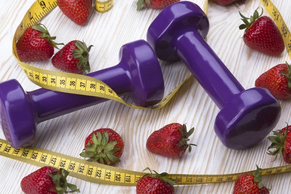 Strawberries, measurement tape and dumbbells