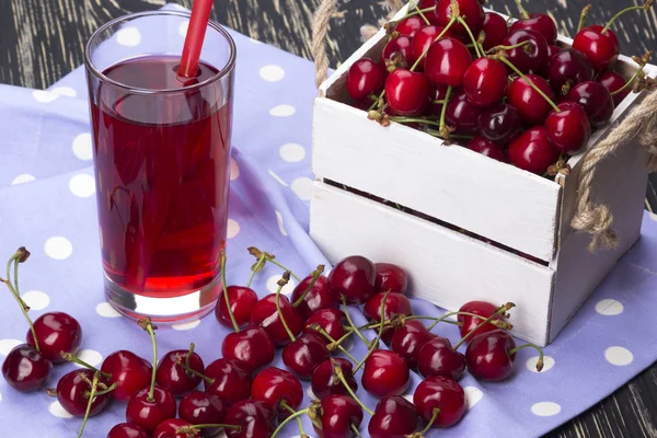 Saft und rote Kirschen in einer Holzkiste — Stockfoto