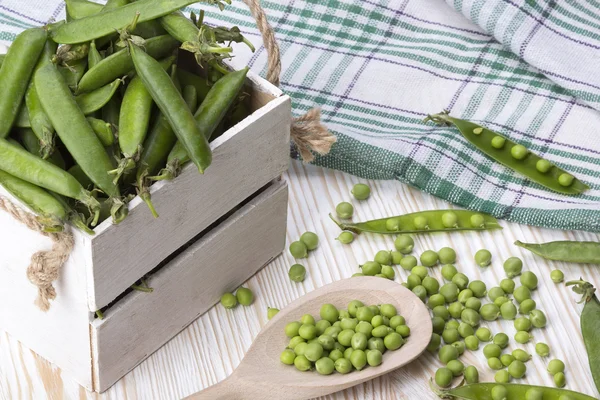 Groene erwten in een houten doos — Stockfoto