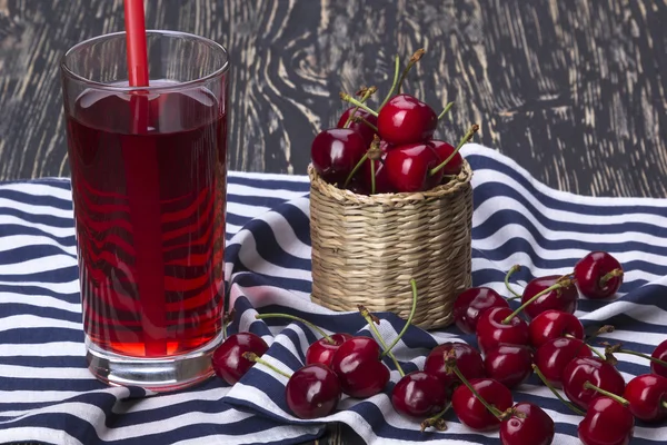 Kirschkorb und Saft auf Holzgrund — Stockfoto