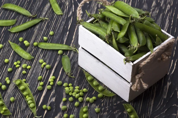 Groene erwten in een houten doos — Stockfoto