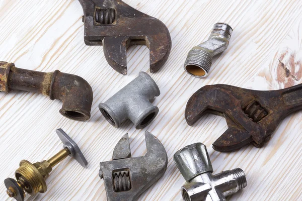 Adjustable wrench and pipes on the wooden background — Stock Photo, Image