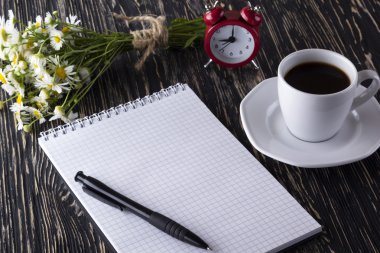 boş defter, çalar saat, charmomile ve kahve fincanı.