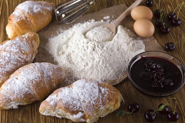 Verse croissants met meel, eieren, cherry jam en handvat mixer. — Stockfoto