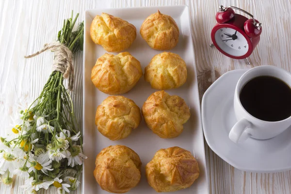 Eclair, Kaffeetasse, Wecker und Charmomille. — Stockfoto