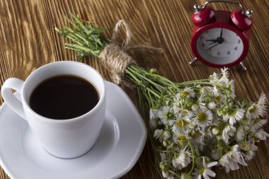 Fincan kahve, papatya ve çalar saat.