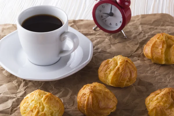 Eclair, Kaffeetasse und Wecker — Stockfoto