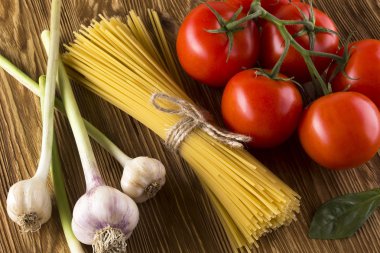 Pişmemiş makarna ve domates, fesleğen, sarımsak malzemelerle.