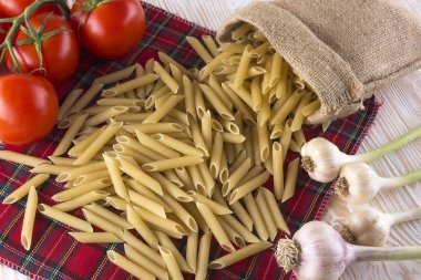 Pişmemiş makarna ve malzemeler ile domates, sarımsak.