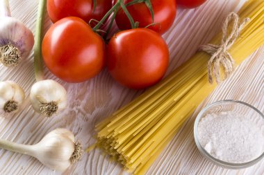 Pişmemiş makarna ve malzemeler ile domates, sarımsak