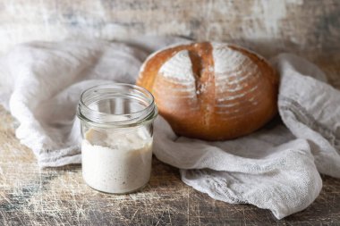 Kavanozda ekmek ve eski bir masada ekmek pişirmek için ekmek. Ev yapımı ekmek. Sağlıklı beslenme kavramı. Seçici odak.