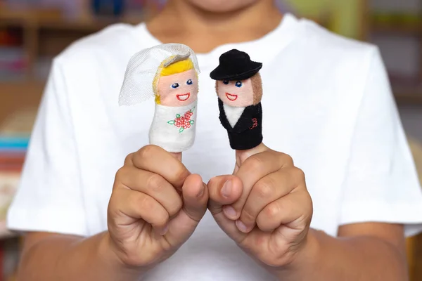 Finger Puppet Theater. Children\'s hand with figures of dolls. Bride and groom. Wedding. Family concept.