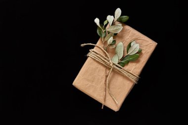 Siyah arka planda şık bir el işi hediye kutusu. Sıfır atık, plastiksiz, el yapımı Noel, doğum günü, Paskalya için hediye paketi. Üst Manzara. Boşluğu kopyala.