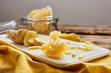 Tahta masada beyaz bir tabakta zencefil dilimleri. Susuz kalmış doğu meyveleri. Sağlıklı tatlılar. Antioksidan.