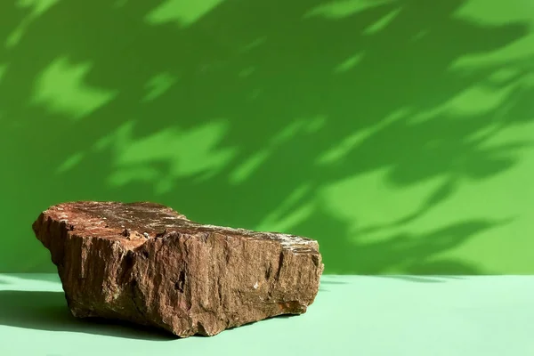 Yaprak gölgeli doğal taş podyum. Yumuşak yeşil arka planda ürün sunumu. Kozmetik ya da güzellik ürünü tanıtım modası minimalist modelleme.