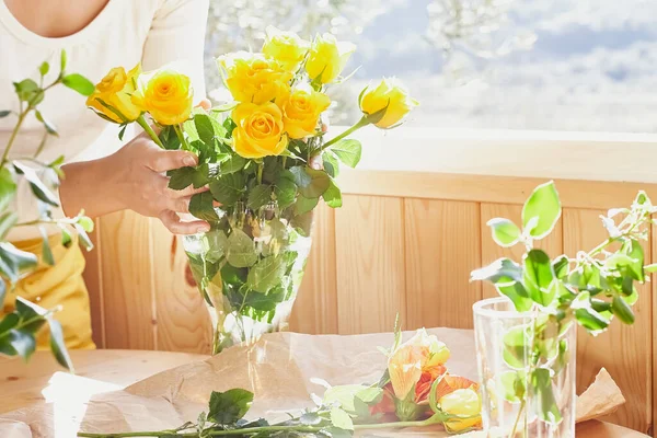Женщина Расставляет Свежие Весенние Желтые Цветы Стеклянной Вазе Деревянном Столе — стоковое фото