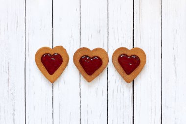 Kalp şeklinde ev yapımı kurabiyeler ve beyaz ahşap arka planda çilek reçeli. Doğum günü, Sevgililer Günü, Anneler Günü. Güzel manzara. Glütensiz un kurabiyesi.
