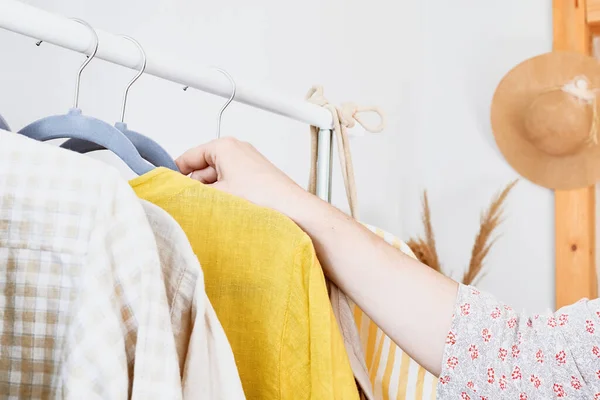 Kadın elbise askılığından keten elbise alıyor. Slow Fashion. Bilinçli tüketim. Moda endüstrisinde kriz, perakende. Çevre dostu, sürdürülebilir mevsimsel satış konsepti. Sıfır atık.