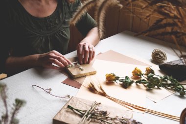 Kadınlar sıfır israf yapıyor, plastiksiz, moda el yapımı geri dönüşümlü kağıt ve masa örtülü kurutulmuş çiçeklerle hediye paketi yapıyor. Doğal Estetik.