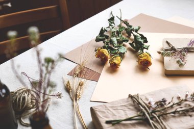 Samimi, sıfır atık, plastiksiz, modaya uygun el yapımı hediye kartı ve el yapımı geri dönüşümlü kağıttan yapılmış hediye kutusu ve masa örtülü kurutulmuş çiçekler. Doğal Estetik.